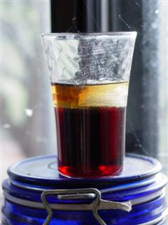 A photo of a shot glass resting on a jar